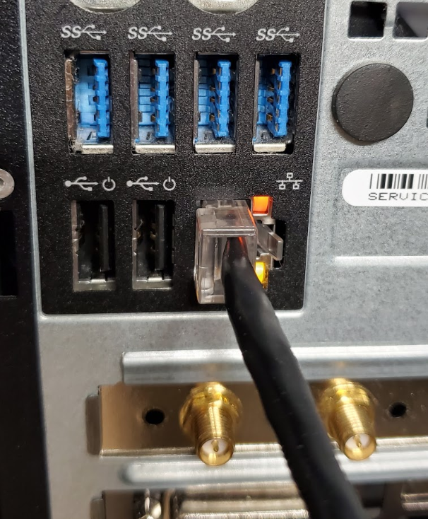 Shows ethernet cable plugged into ethernet network port on back of tower PC